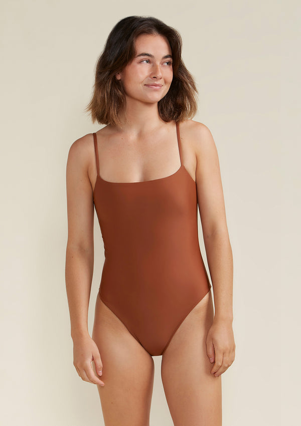 Model wearing Tama Swim Harlow one piece swimsuit in colour earth