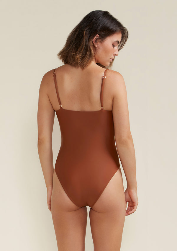 Model wearing Tama Swim Harlow one piece swimsuit in colour earth back view