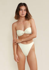 Model wears Tama Swim Frankie bandeau bikini top in white dusk colour