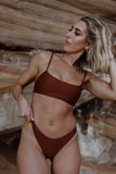 Model wearing blake bikini top and bottom posing against rocks in tamarama